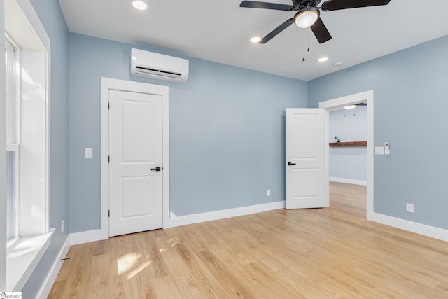 unfurnished bedroom featuring a wall mounted air conditioner, light wood-type flooring, and ceiling fan