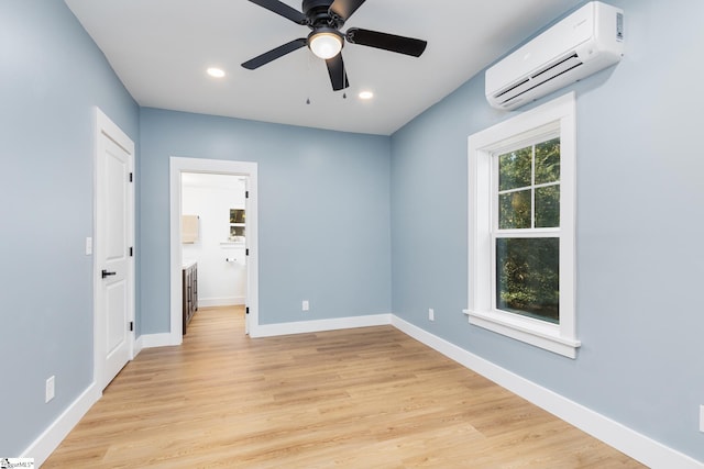 unfurnished room with ceiling fan, light hardwood / wood-style flooring, and a wall mounted air conditioner