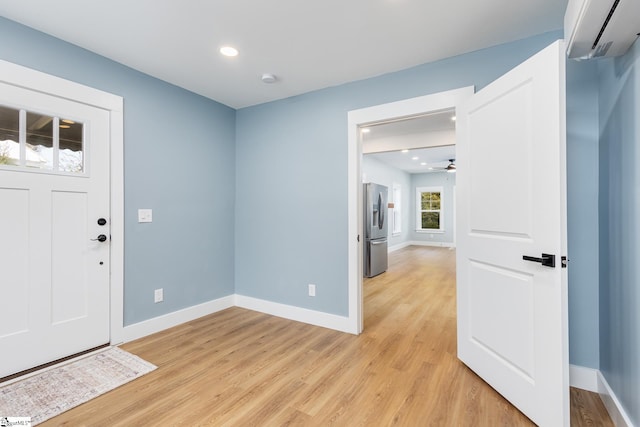 entrance foyer featuring a wall mounted AC, light wood-type flooring, and ceiling fan