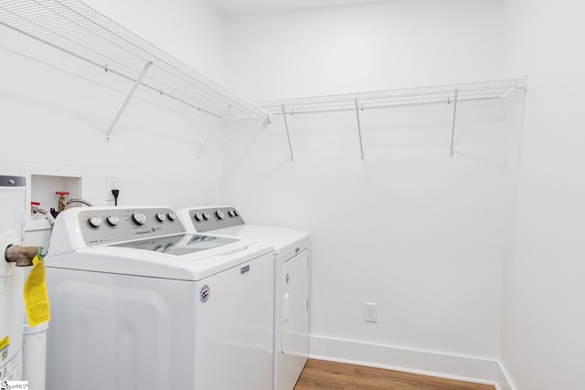 clothes washing area featuring hardwood / wood-style floors and washer and clothes dryer