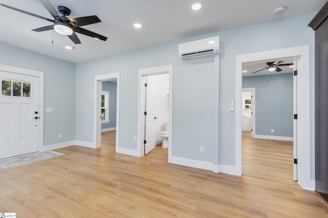 foyer entrance with light hardwood / wood-style floors, a wall mounted AC, and ceiling fan