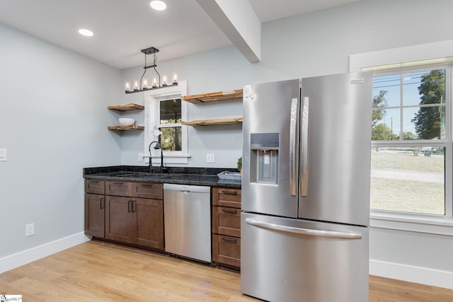 kitchen featuring dark stone countertops, stainless steel appliances, light hardwood / wood-style flooring, and decorative light fixtures