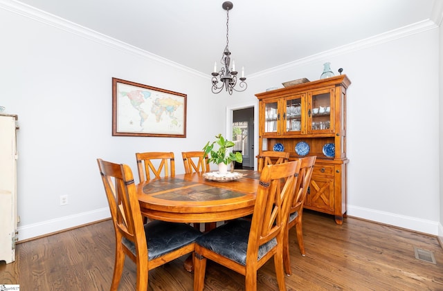 dining area featuring ornamental molding, dark wood-type flooring, and a chandelier