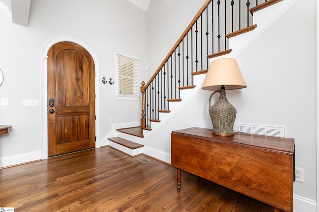 foyer entrance with high vaulted ceiling and dark hardwood / wood-style flooring