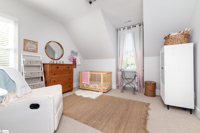 carpeted bedroom with vaulted ceiling and a nursery area