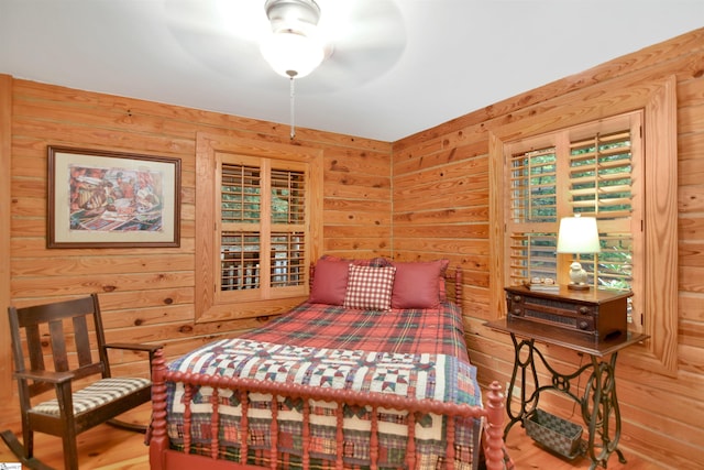 bedroom with wood walls, hardwood / wood-style floors, and ceiling fan