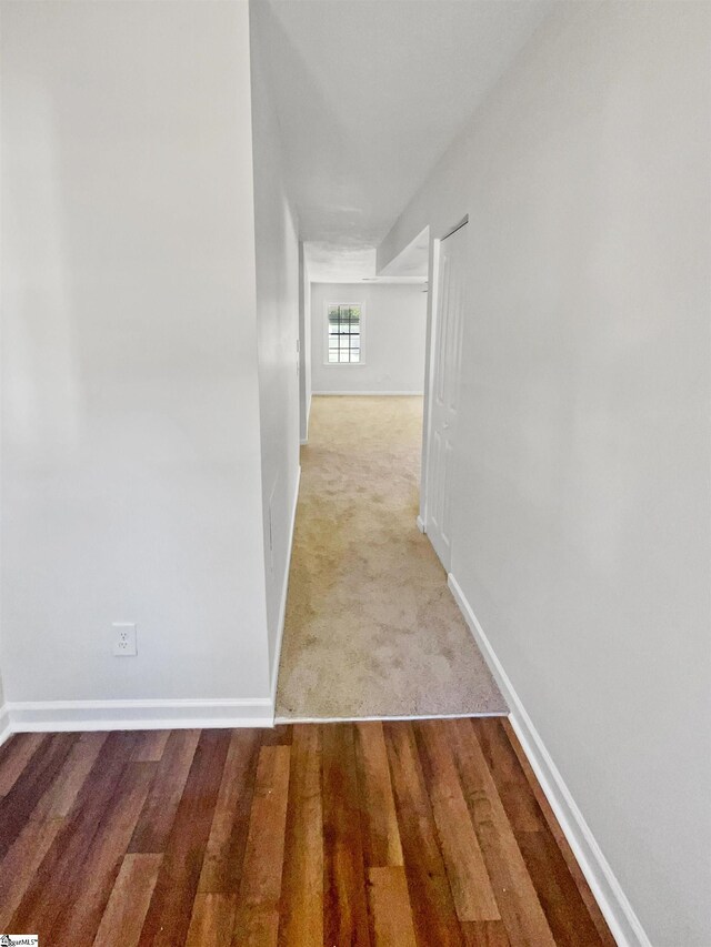 corridor featuring baseboards and wood finished floors