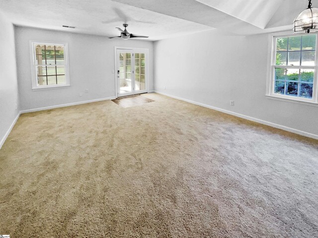 empty room featuring carpet floors, a ceiling fan, baseboards, and plenty of natural light