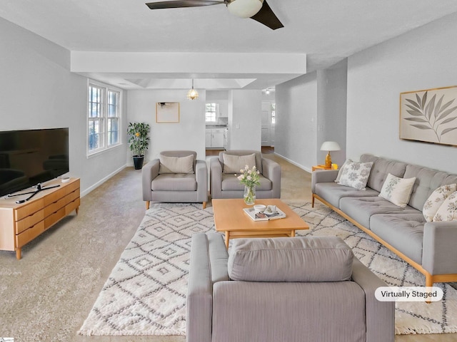 carpeted living area featuring baseboards, ceiling fan, and a healthy amount of sunlight