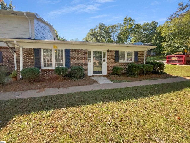 view of front facade with brick siding and a front lawn