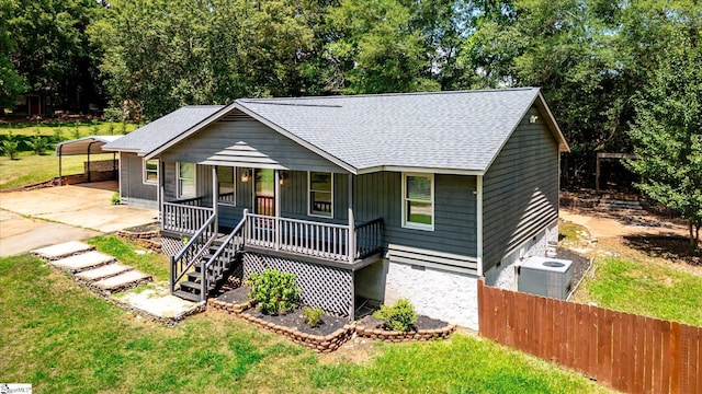 ranch-style home featuring central air condition unit, a carport, a front yard, and a porch