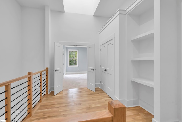 corridor featuring light hardwood / wood-style flooring and built in shelves