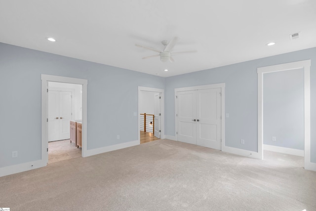 unfurnished bedroom featuring light carpet, connected bathroom, and ceiling fan