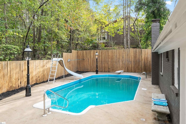 view of pool featuring a water slide, a diving board, and a patio