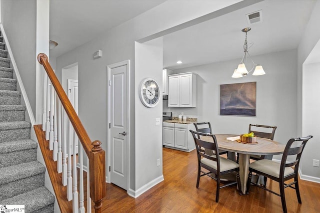 dining area with wood-type flooring and an inviting chandelier