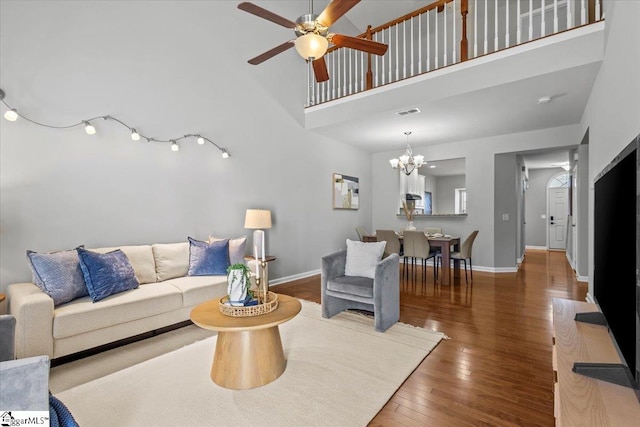 living room featuring ceiling fan with notable chandelier, hardwood / wood-style flooring, and a towering ceiling