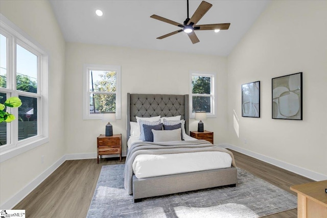 bedroom with lofted ceiling, hardwood / wood-style flooring, multiple windows, and ceiling fan