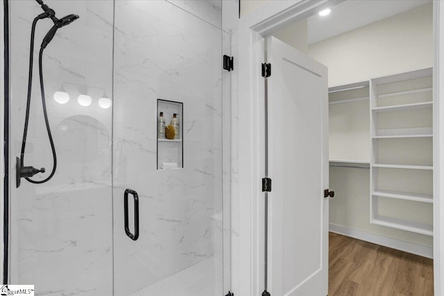 bathroom with a shower with shower door and hardwood / wood-style floors