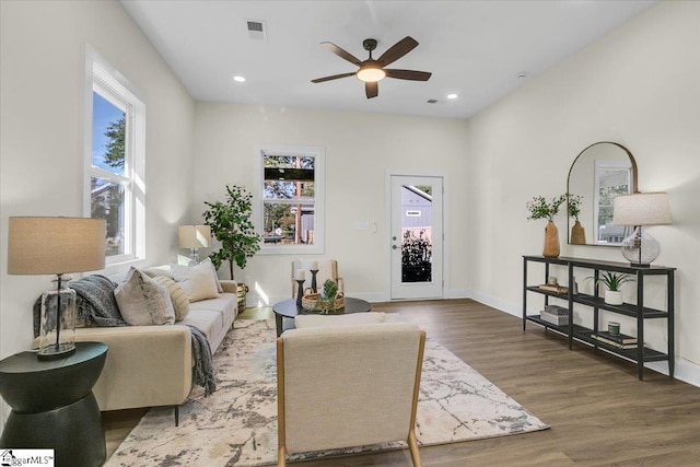 living room with dark hardwood / wood-style flooring, ceiling fan, and a wealth of natural light