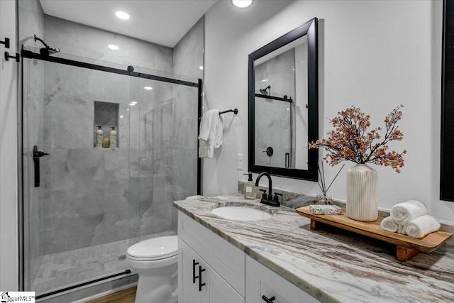 bathroom featuring vanity, toilet, wood-type flooring, and a shower with shower door