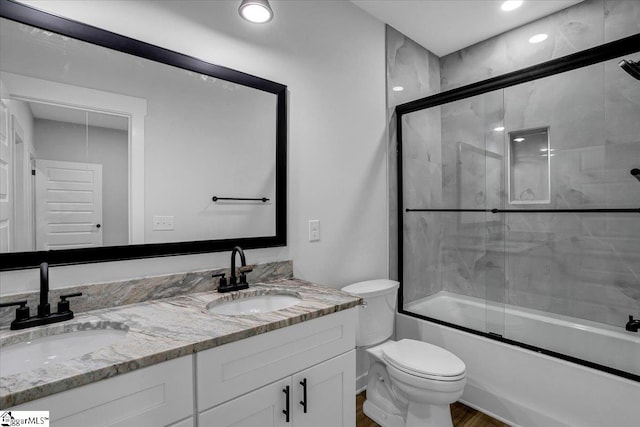 full bathroom with vanity, toilet, hardwood / wood-style flooring, and shower / bath combination with glass door