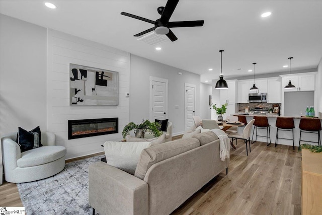 living room featuring light hardwood / wood-style flooring, a fireplace, and ceiling fan