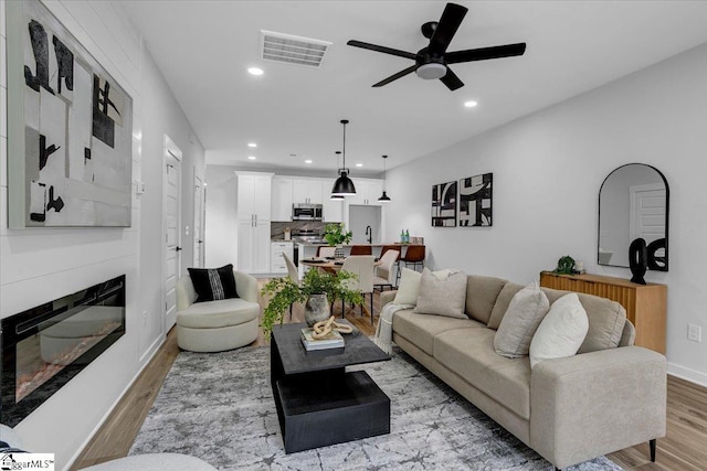 living room featuring light wood-type flooring and ceiling fan