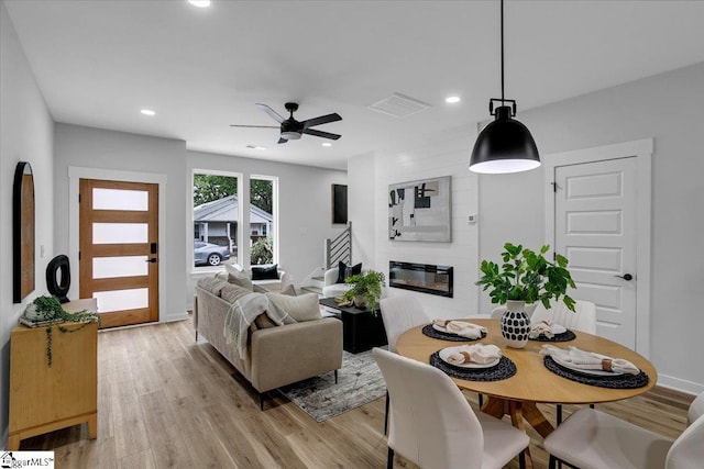 living room featuring light hardwood / wood-style floors, a large fireplace, and ceiling fan