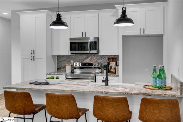 kitchen with appliances with stainless steel finishes, white cabinets, decorative light fixtures, and backsplash