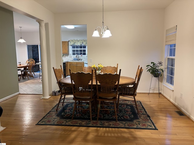 dining space featuring light wood finished floors, decorative columns, visible vents, and baseboards