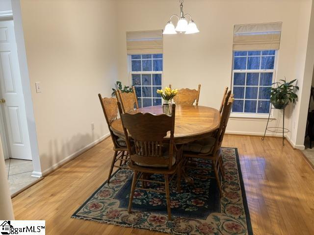 dining room featuring baseboards, wood finished floors, and a notable chandelier