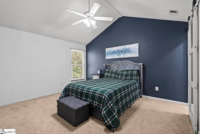 carpeted bedroom with a closet, a barn door, vaulted ceiling, and ceiling fan