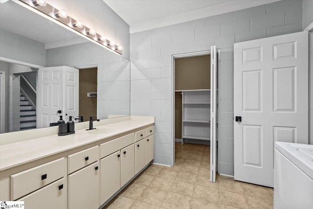 bathroom featuring vanity, washer / clothes dryer, and tile walls