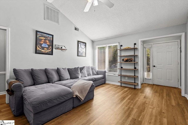 living room featuring light hardwood / wood-style floors, high vaulted ceiling, a textured ceiling, and ceiling fan