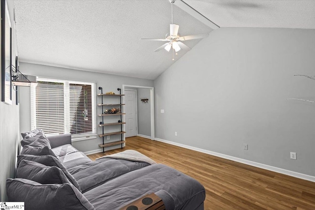 living room with lofted ceiling, a textured ceiling, wood-type flooring, and ceiling fan