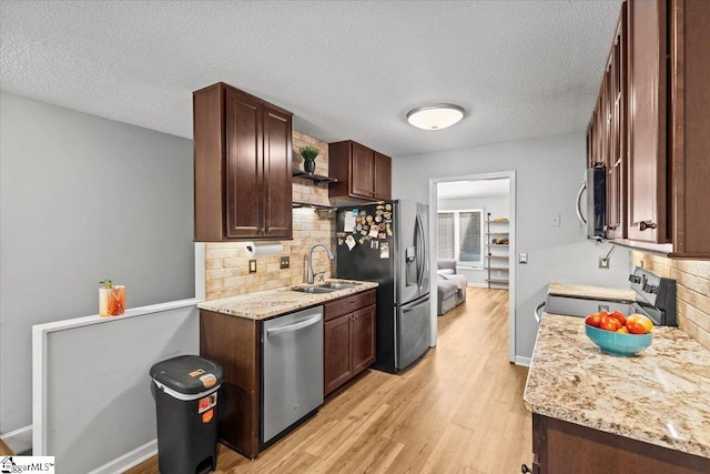 kitchen with tasteful backsplash, appliances with stainless steel finishes, a textured ceiling, light wood-type flooring, and sink