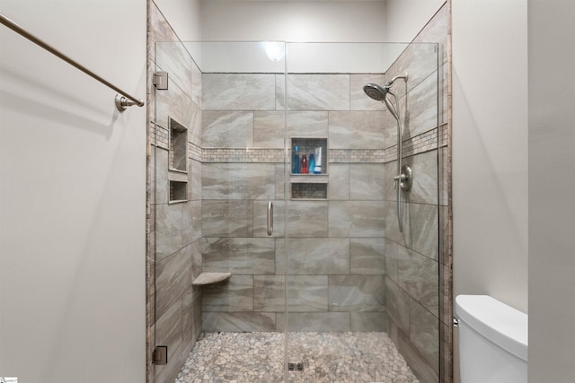 bathroom featuring a shower with shower door and toilet