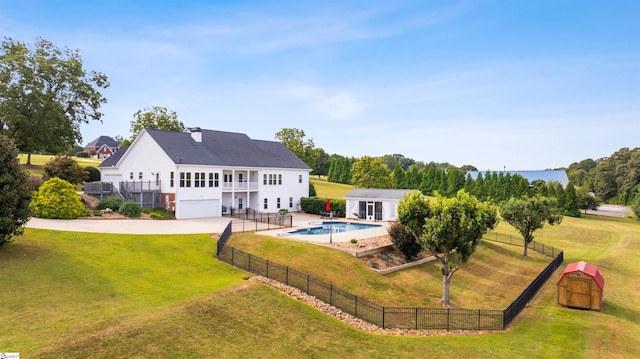 back of house with a yard, a garage, a fenced in pool, a patio area, and a balcony