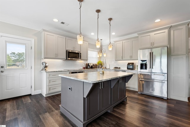 kitchen featuring appliances with stainless steel finishes, hanging light fixtures, crown molding, decorative backsplash, and dark hardwood / wood-style floors