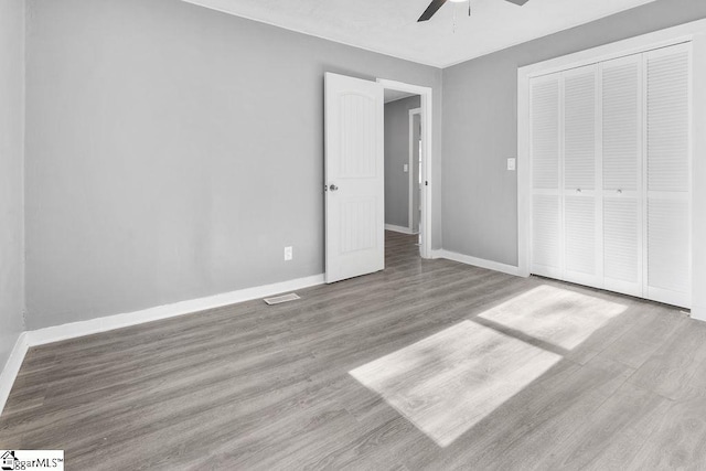 unfurnished bedroom featuring ceiling fan, light hardwood / wood-style floors, and a closet