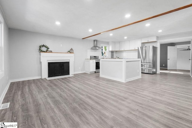 unfurnished living room featuring sink, ceiling fan, and light wood-type flooring