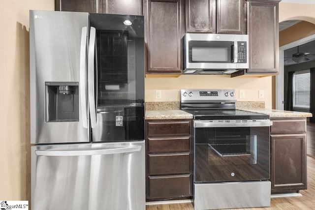 kitchen featuring appliances with stainless steel finishes, dark brown cabinetry, and light wood-type flooring