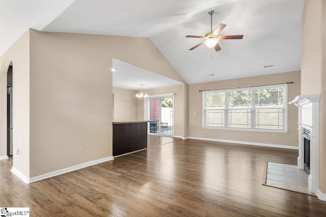 unfurnished living room with high vaulted ceiling, wood-type flooring, and ceiling fan with notable chandelier