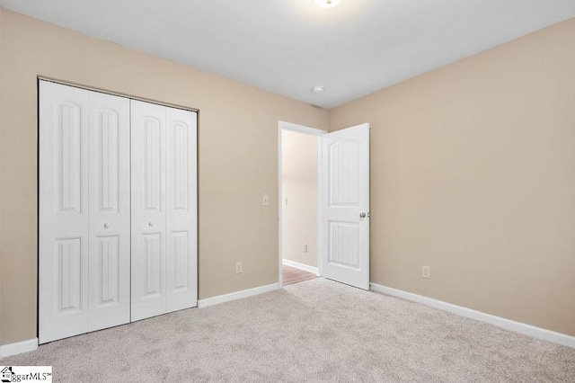 unfurnished bedroom with a closet and light colored carpet