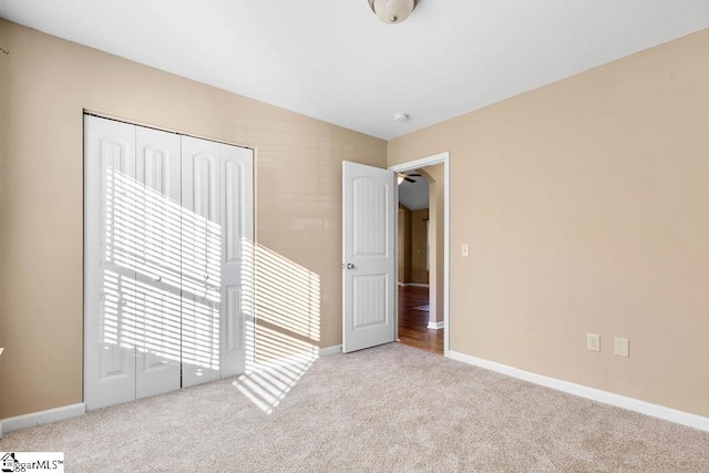 unfurnished bedroom featuring light carpet and a closet