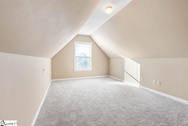 additional living space featuring light carpet and vaulted ceiling