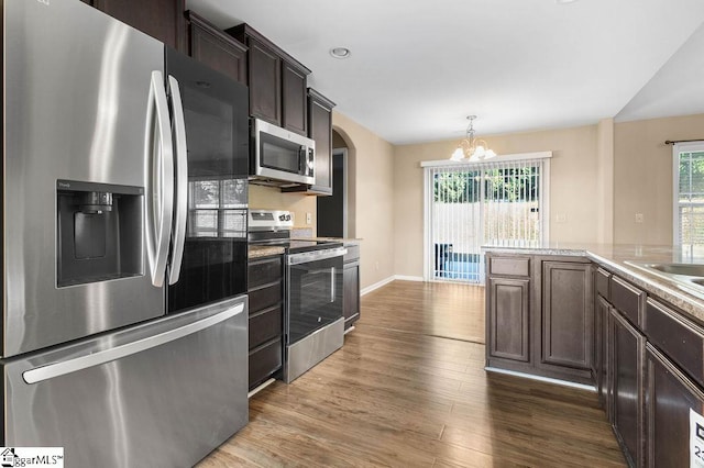 kitchen featuring dark brown cabinets, hanging light fixtures, stainless steel appliances, an inviting chandelier, and dark hardwood / wood-style floors