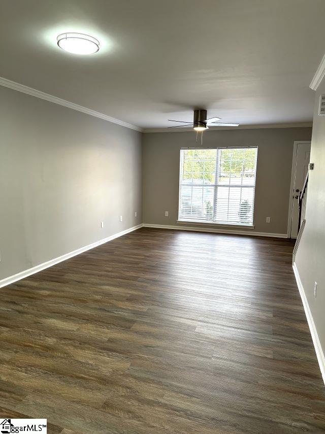 empty room with dark wood-type flooring, crown molding, and ceiling fan