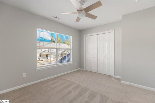 unfurnished bedroom with light carpet, a closet, and ceiling fan