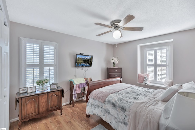 bedroom featuring light hardwood / wood-style flooring, a textured ceiling, and ceiling fan